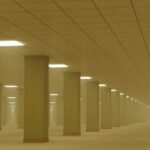 Backrooms: Πώς γεννήθηκε ο ανατριχιαστικός μύθος του ίντερνετ Άδειος κίτρινος διάδρομος με φωτισμό οροφής, εικόνα που παραπέμπει στην αισθητική των Backrooms
