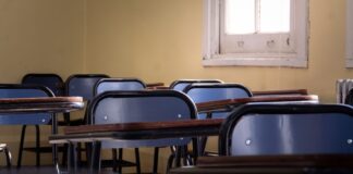 Άδεια σχολική αίθουσα με θρανία και καρέκλες δίπλα σε παράθυρο