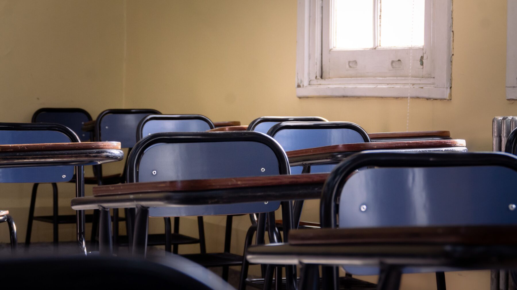Άδεια σχολική αίθουσα με θρανία και καρέκλες δίπλα σε παράθυρο