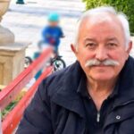 Ο Γιάννης Πανταζής καθισμένος σε παγκάκι, σε υπαίθριο χώρο
