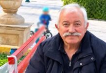 Ο Γιάννης Πανταζής καθισμένος σε παγκάκι, σε υπαίθριο χώρο