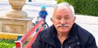 Ο Γιάννης Πανταζής καθισμένος σε παγκάκι, σε υπαίθριο χώρο