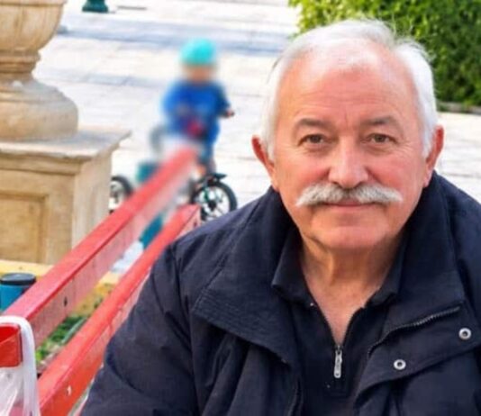 Ο Γιάννης Πανταζής καθισμένος σε παγκάκι, σε υπαίθριο χώρο